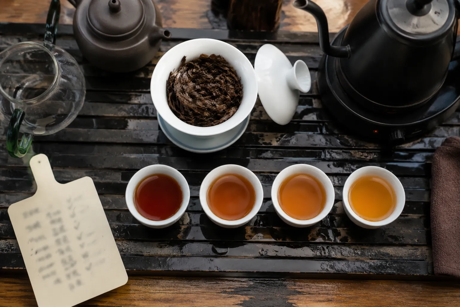 A gongfu black tea session with several small cups showing darker and lighter infusions as temperature and time are adjusted