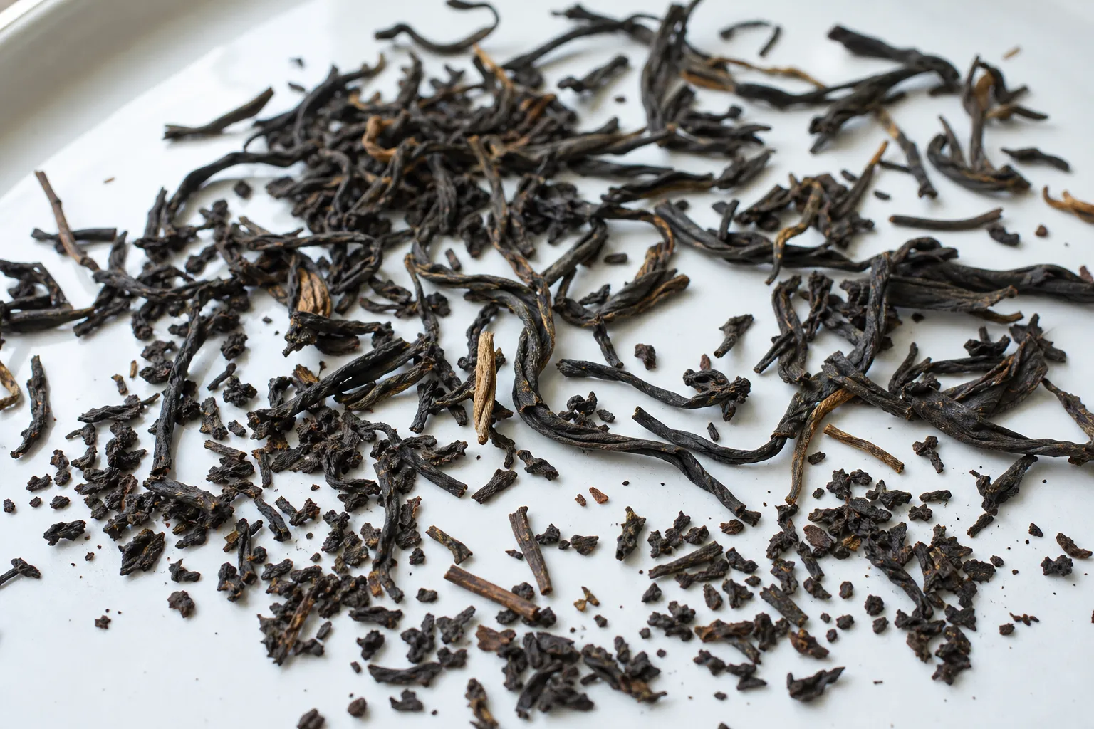 Close view of dry whole leaf black tea with visible size variation, tips, dust, and broken pieces